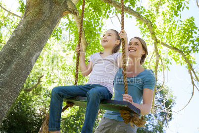 Happy mother swinging daughter at park