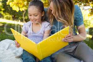 Happy mother and daughter reading a book