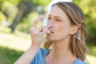 Woman using asthma inhaler in park