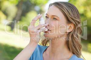 Woman using asthma inhaler in park