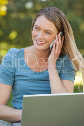 Relaxed woman using laptop and mobile phone at park