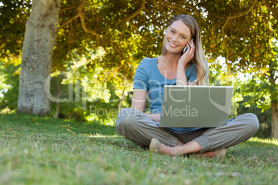 Relaxed woman using laptop and mobile phone at park