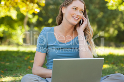 Relaxed woman using laptop and mobile phone at park