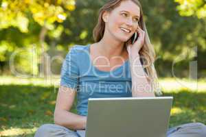 Relaxed woman using laptop and mobile phone at park