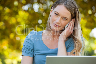 Relaxed woman using laptop and mobile phone at park