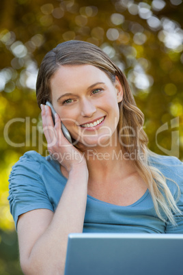 Relaxed woman using laptop and mobile phone at park