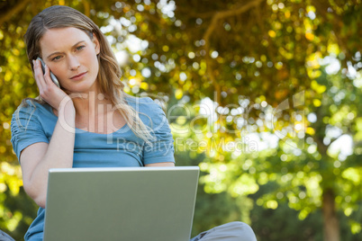 Relaxed woman using laptop and mobile phone at park