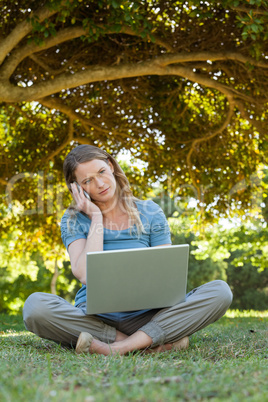 Relaxed woman using laptop and mobile phone at park