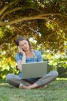 Relaxed woman using laptop and mobile phone at park