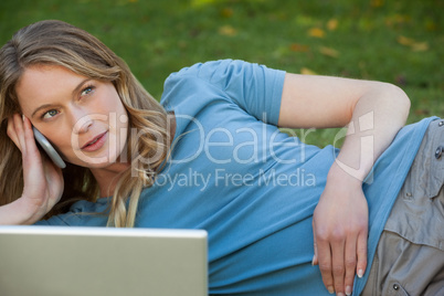 Relaxed woman using laptop and mobile phone at park