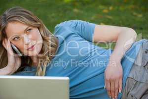 Relaxed woman using laptop and mobile phone at park
