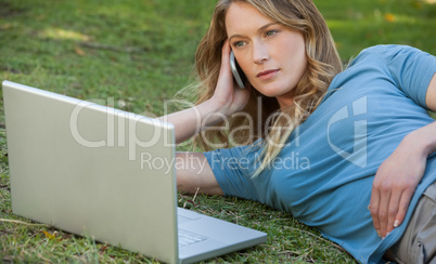 Woman using laptop and mobile phone at park