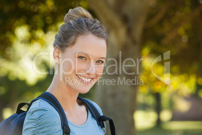 Beautiful young woman with backpack at park