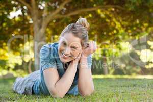 Beautiful relaxed young woman lying on grass at park