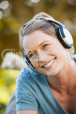 Beautiful young woman enjoying music in park