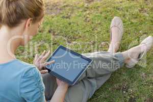 Relaxed young woman using digital tablet at park