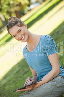 Young woman using digital tablet at park