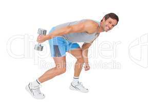 Smiling fit young man exercising with dumbbell