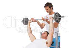 Trainer helping fit man to lift the barbell bench press