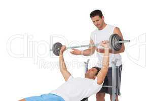Trainer helping fit man to lift the barbell bench press