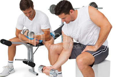 Two fit young men exercising with dumbbells