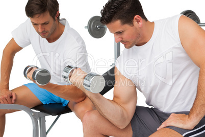 Two fit young men exercising with dumbbells