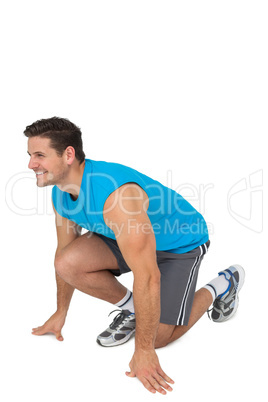 Side view of a sporty smiling man in running stance