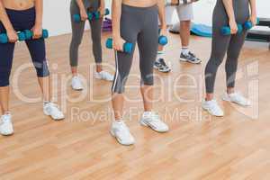 Low section of women exercising with dumbbells in gym