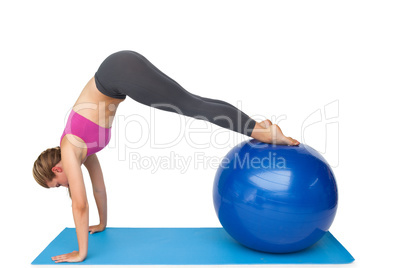 Side view of a fit woman stretching on fitness ball