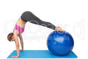 Side view of a fit woman stretching on fitness ball