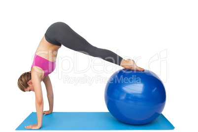 Side view of a fit young woman stretching on fitness ball