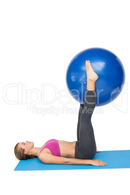 Side view of a fit woman exercising with fitness ball