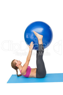 Side view of a fit woman exercising with fitness ball