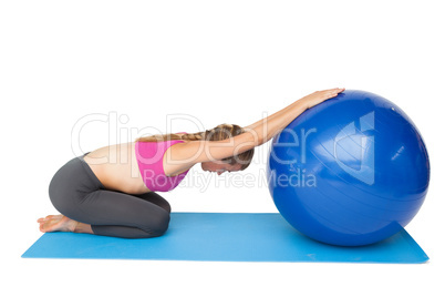 Side view of a fit young woman exercising with fitness ball