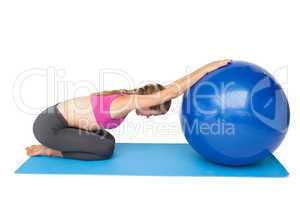Side view of a fit young woman exercising with fitness ball