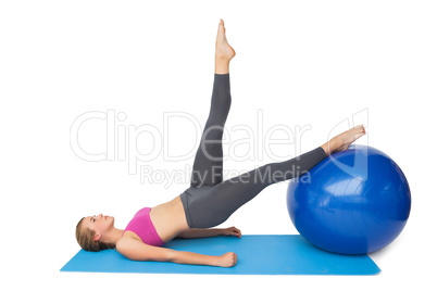 Side view of a fit woman exercising with fitness ball