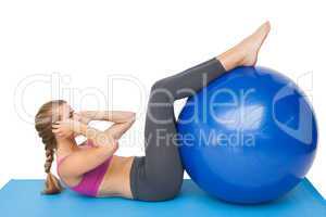 Side view of a fit woman exercising with fitness ball