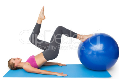 Side view of a fit woman exercising with fitness ball