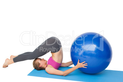 Side view of a fit woman exercising with fitness ball