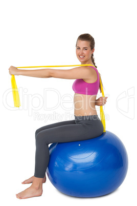 Full length portrait of fit woman exercising on fitness ball