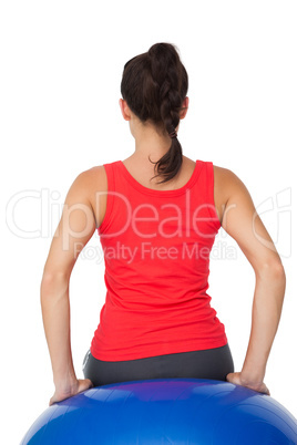 Rear view of a fit woman sitting on exercise ball