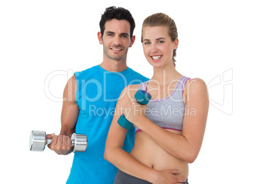 Portrait of a fit couple exercising with dumbbells