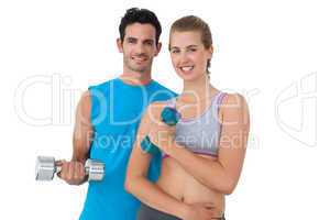Portrait of a fit couple exercising with dumbbells