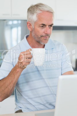 Casual man looking at his laptop while having coffee