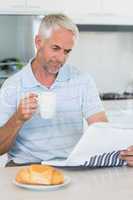 Happy man reading the newspaper at breakfast