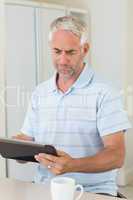 Happy man using his tablet at breakfast