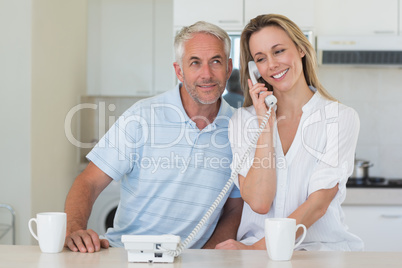 Smiling man listening in on his partners phone call