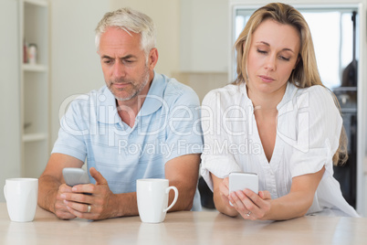 Bored couple sitting at the counter texting