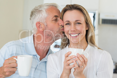 Casual man giving his smiling partner a kiss on the cheek