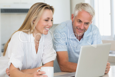 Happy couple using laptop together at the counter